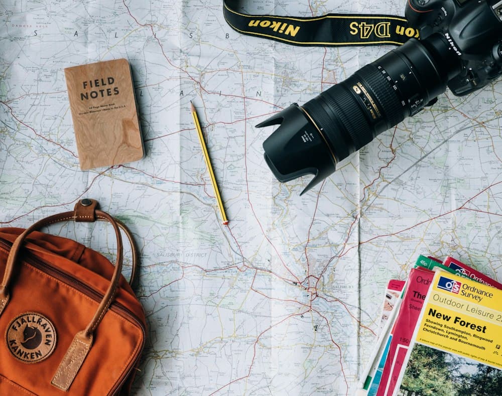 Travel essentials - map, camera and notebook - laid out on a table