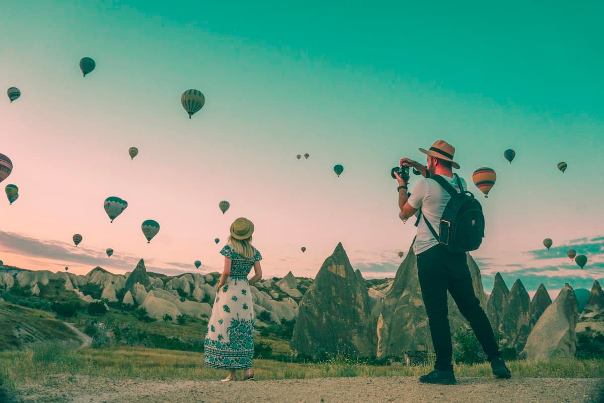 Traveller photographing hot air balloons at sunrise