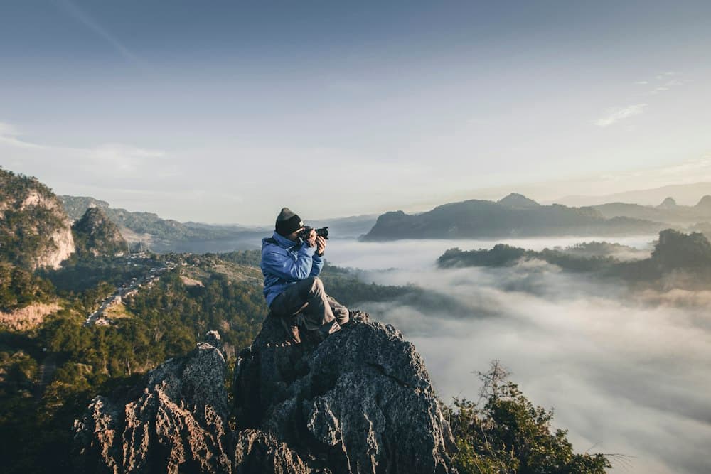 Photographer shooting from a cliff above the clouds