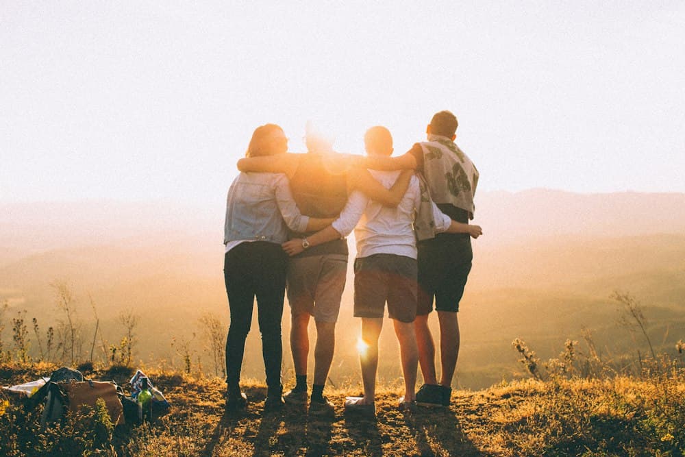 Group of friends hugging at sunset